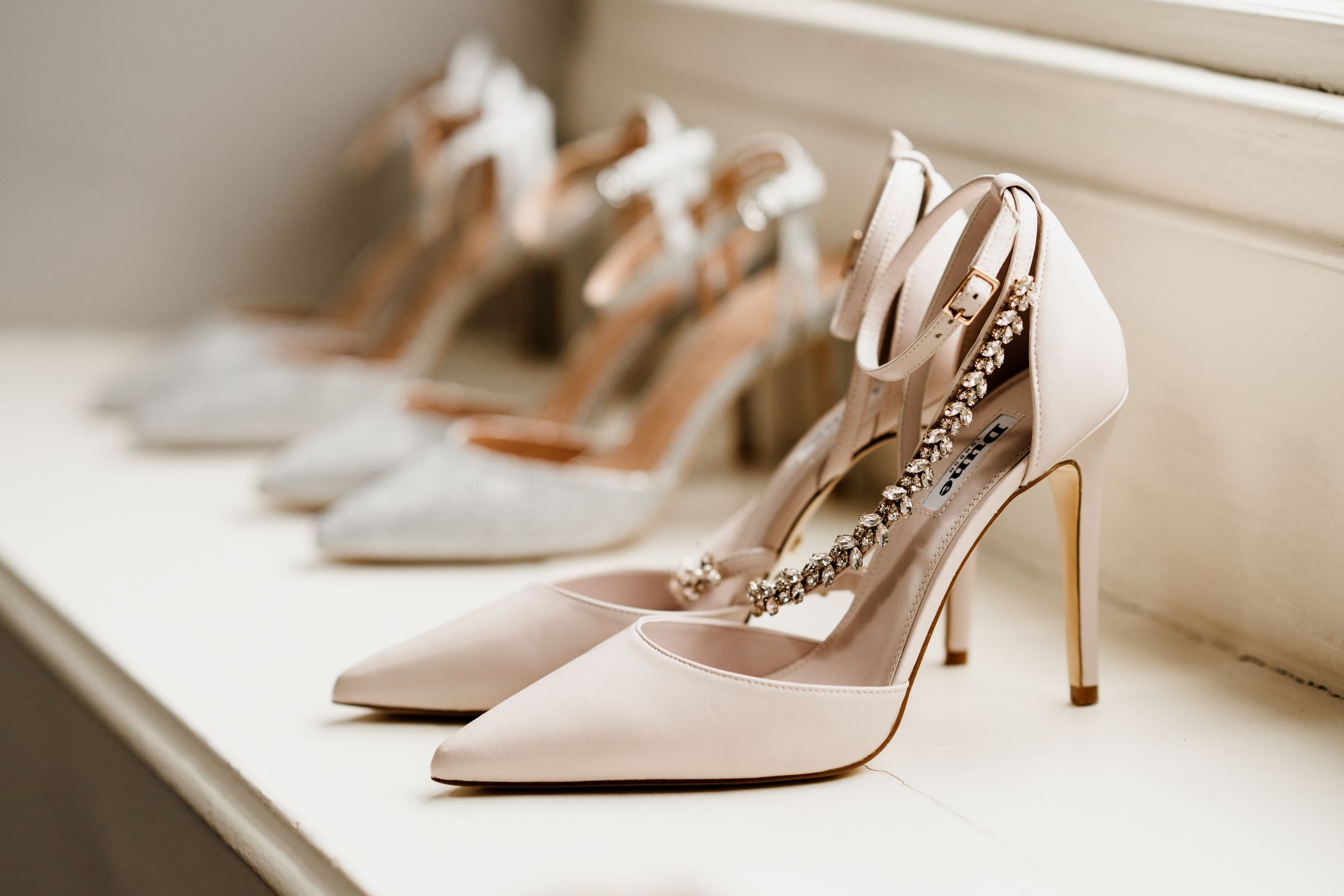Elegant nude high heeled shoes lined up on a shelf showing bridal wedding footwear details.