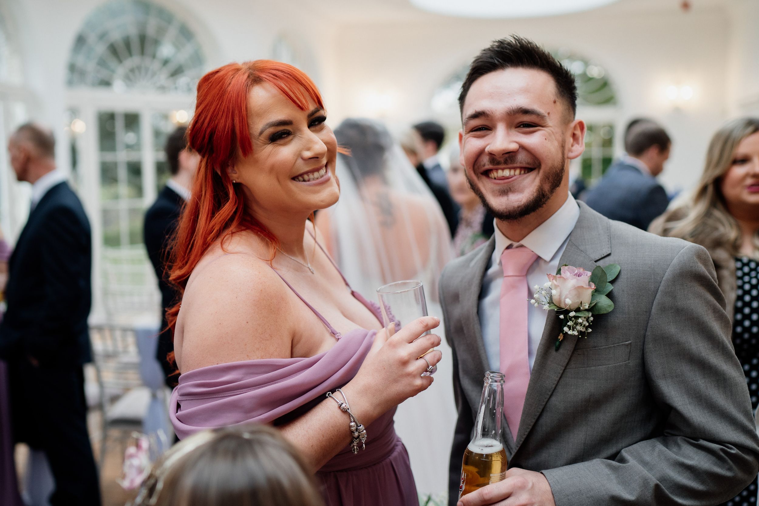 Wedding guests in formal attire share a laugh during the reception celebration.