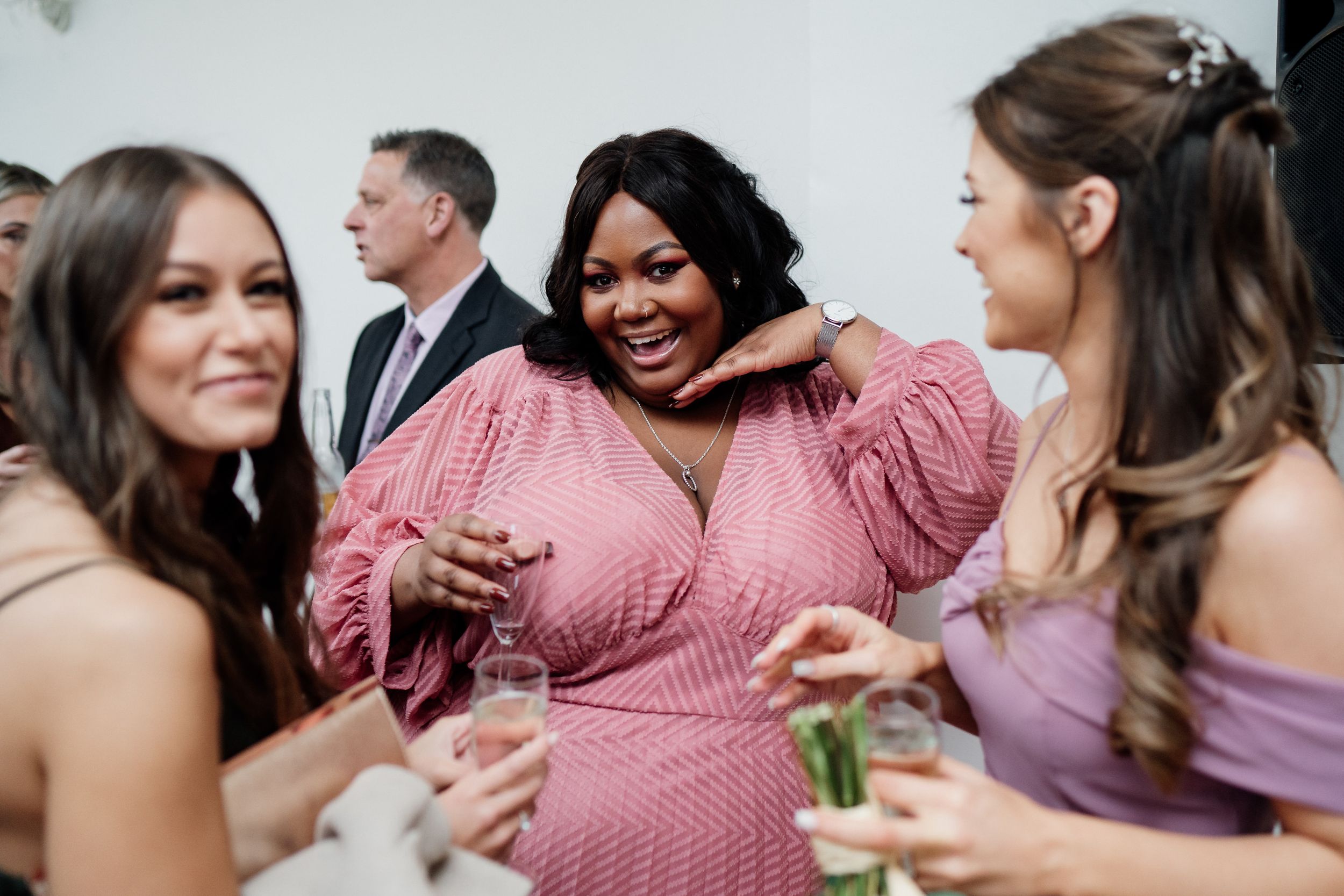 Wedding guests share drinks and laughter during a joyful reception celebration.