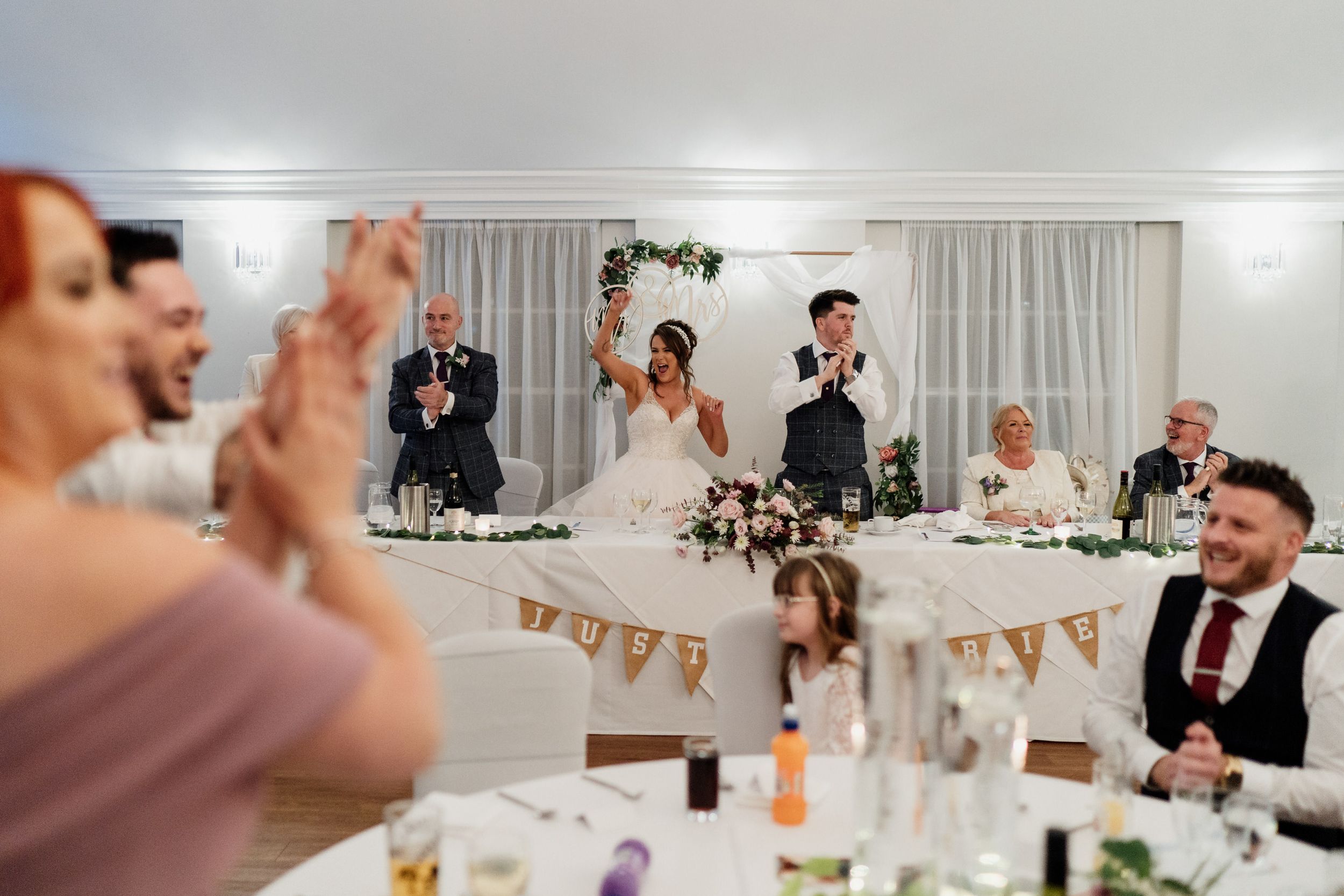 Wedding celebration in full swing at Barton Hall with guests applauding at decorated reception tables.