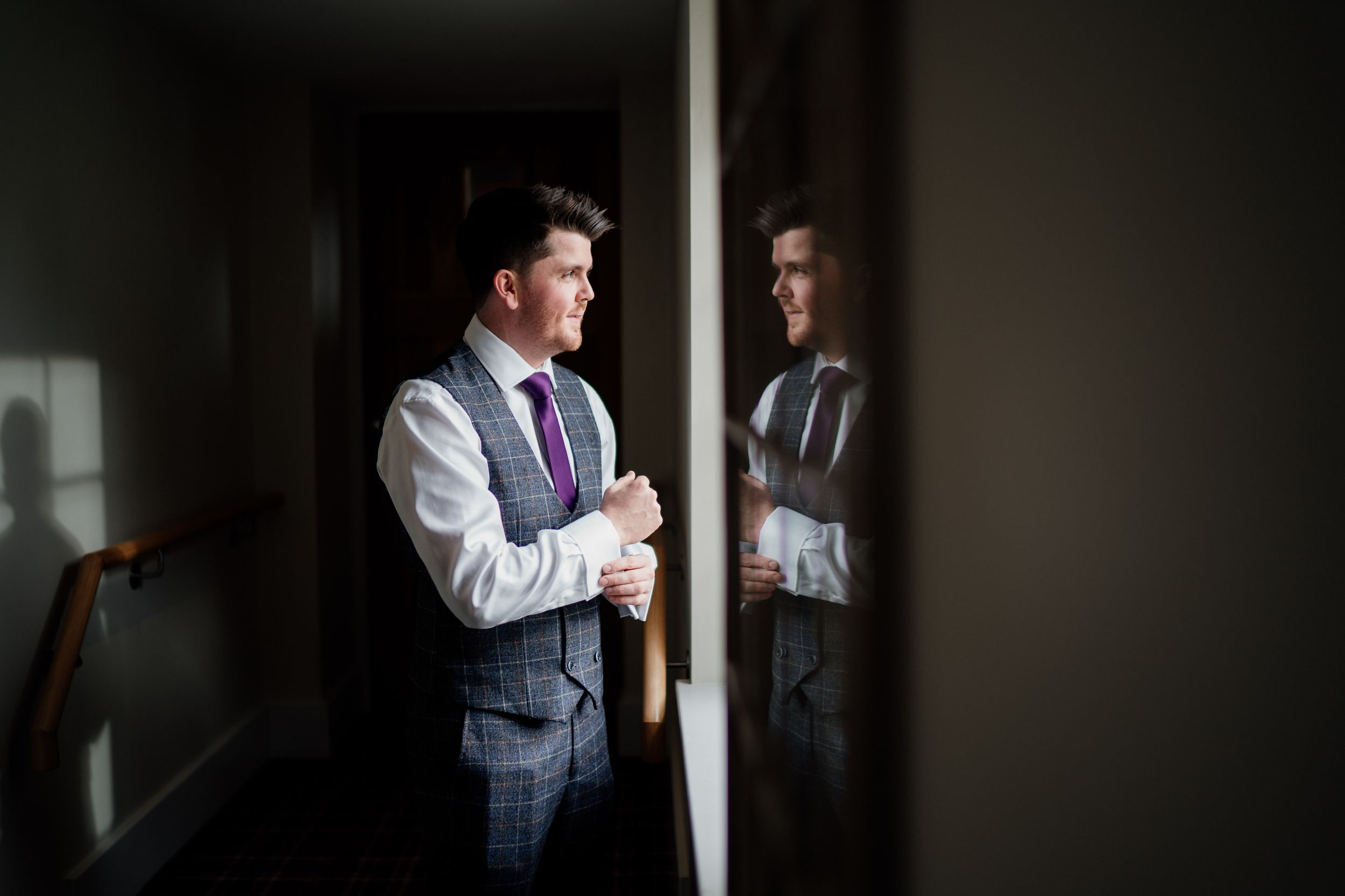 Artistic reflection of formal attire in window light showing preparation moments.