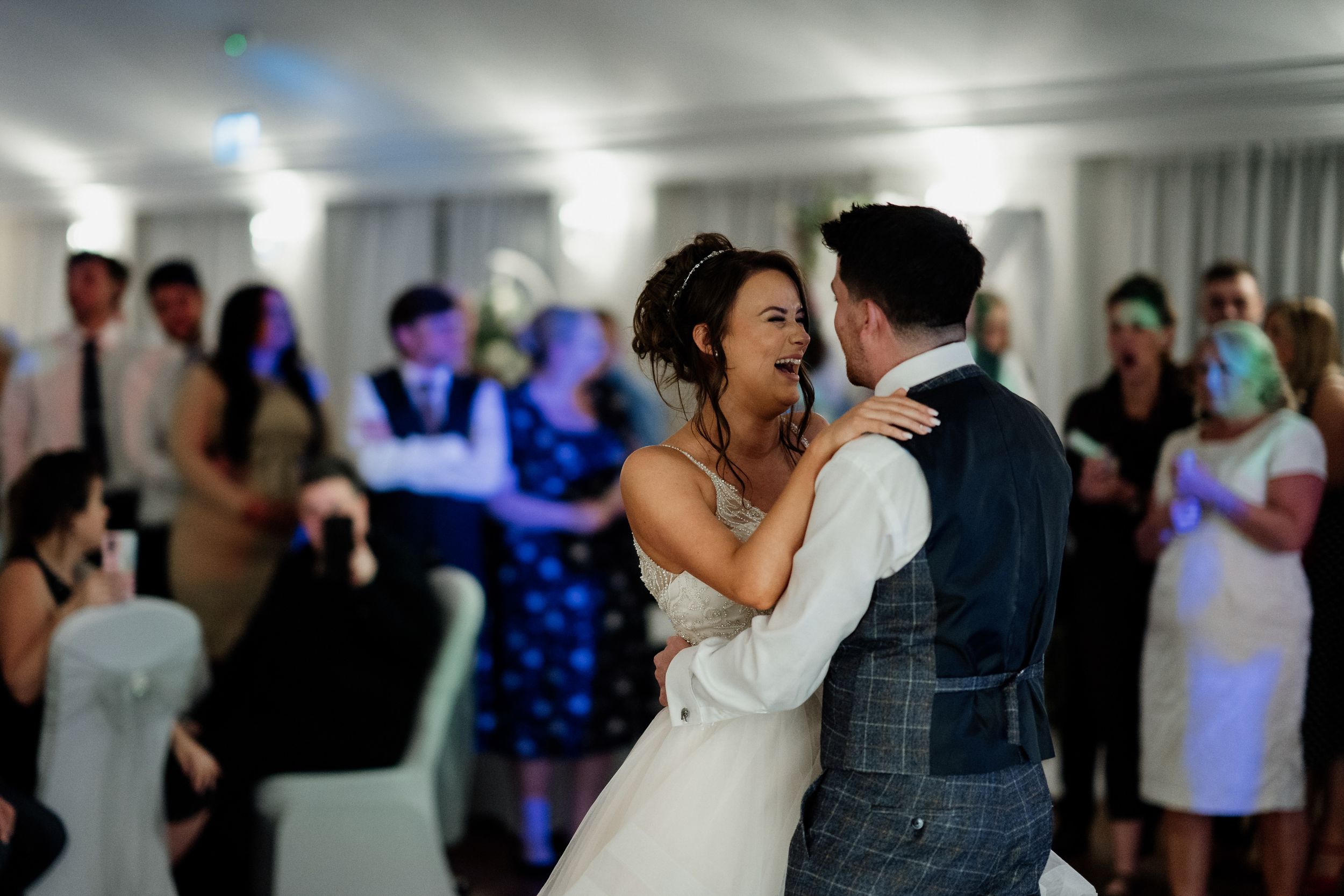 Couple shares a romantic dance moment during their wedding reception with blue lighting effects.
