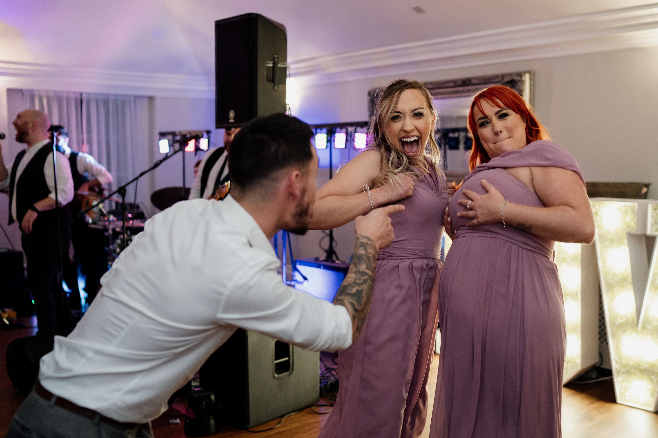 Wedding guests having fun and interacting near the dance floor with band equipment visible.