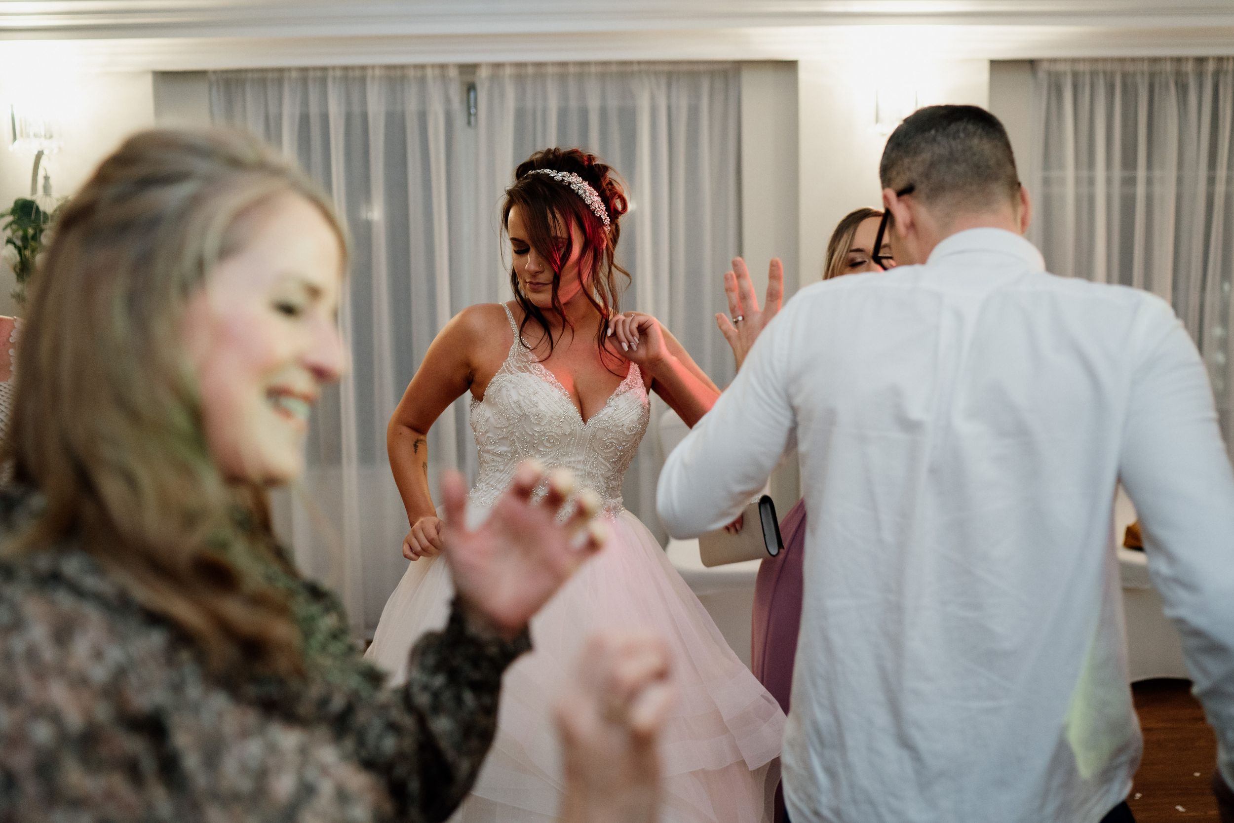 Wedding guests dancing and celebrating at a reception with white curtained walls.