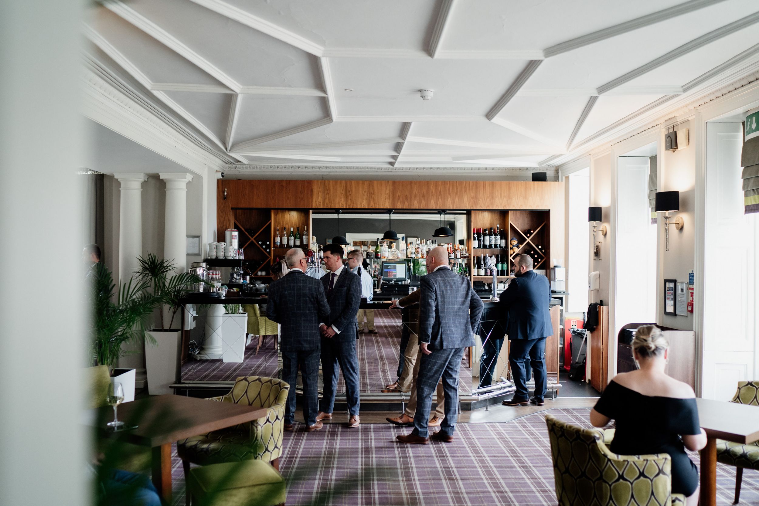 Wedding guests mingling in an upscale hotel lounge with modern decor.
