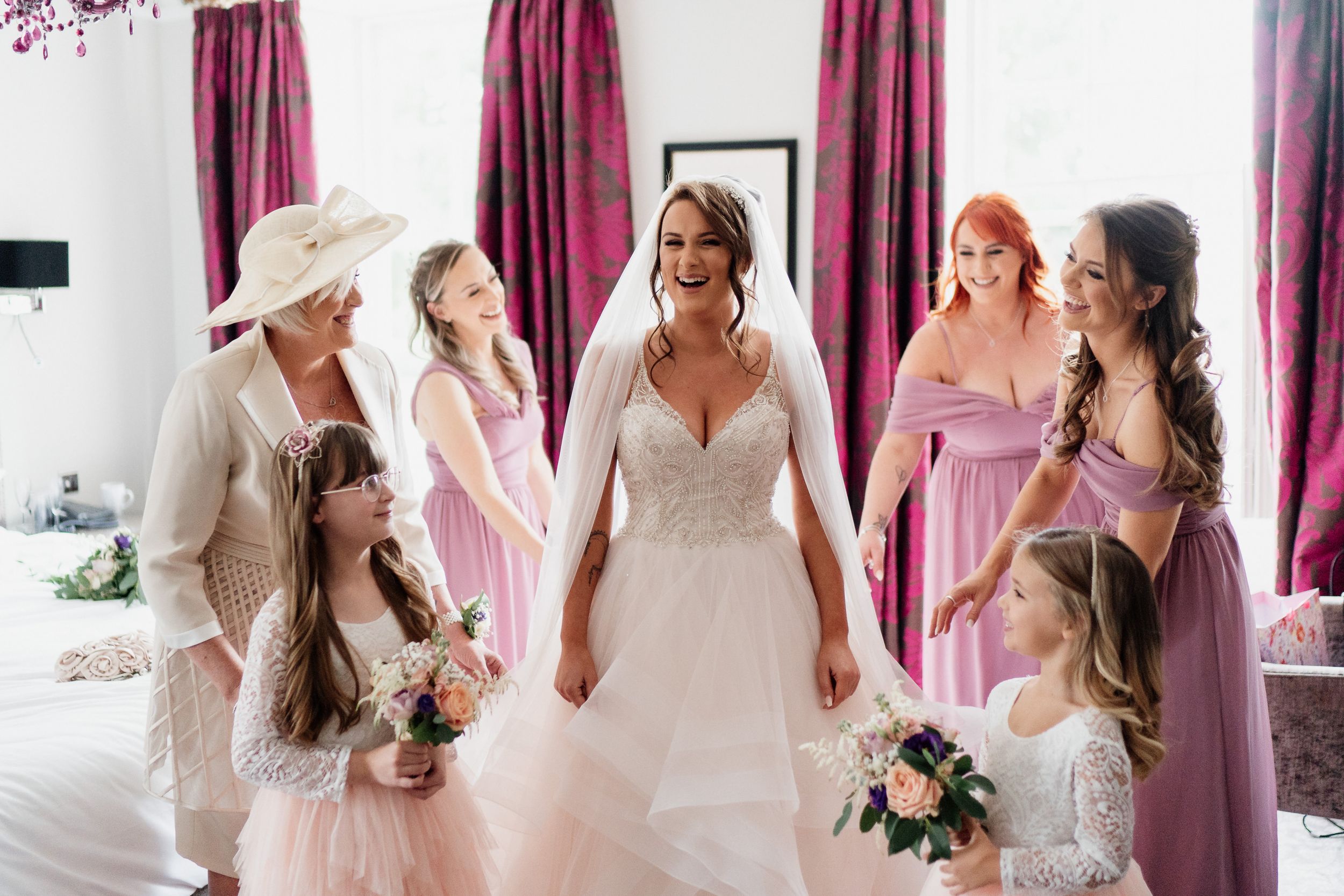 Wedding party gathered in pink and dusty rose dresses during preparation.