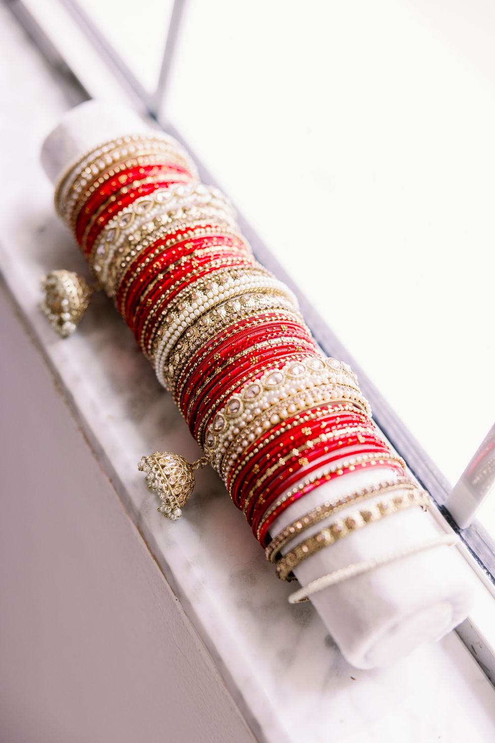 Traditional red and white wedding bangles and bracelets arranged on a display stand.