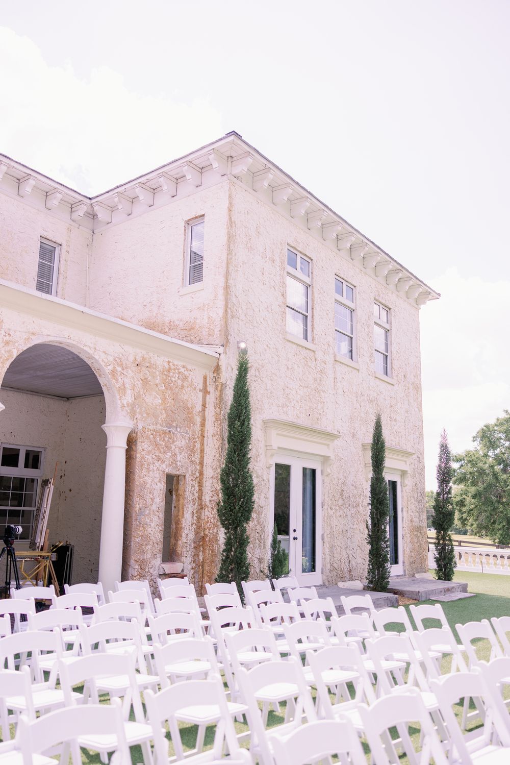 Elegant white wedding venue with Mediterranean architecture and rows of white chairs set up for an outdoor ceremony.