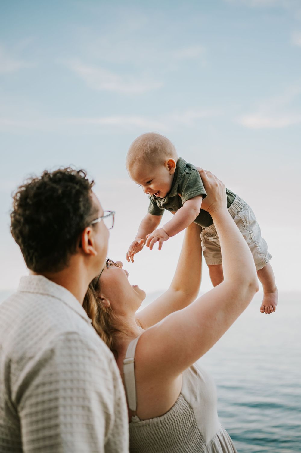 Candid photo of family holding baby at Neck Point Park Nanaimo during golden hour family photography by Vancouver Island photographer