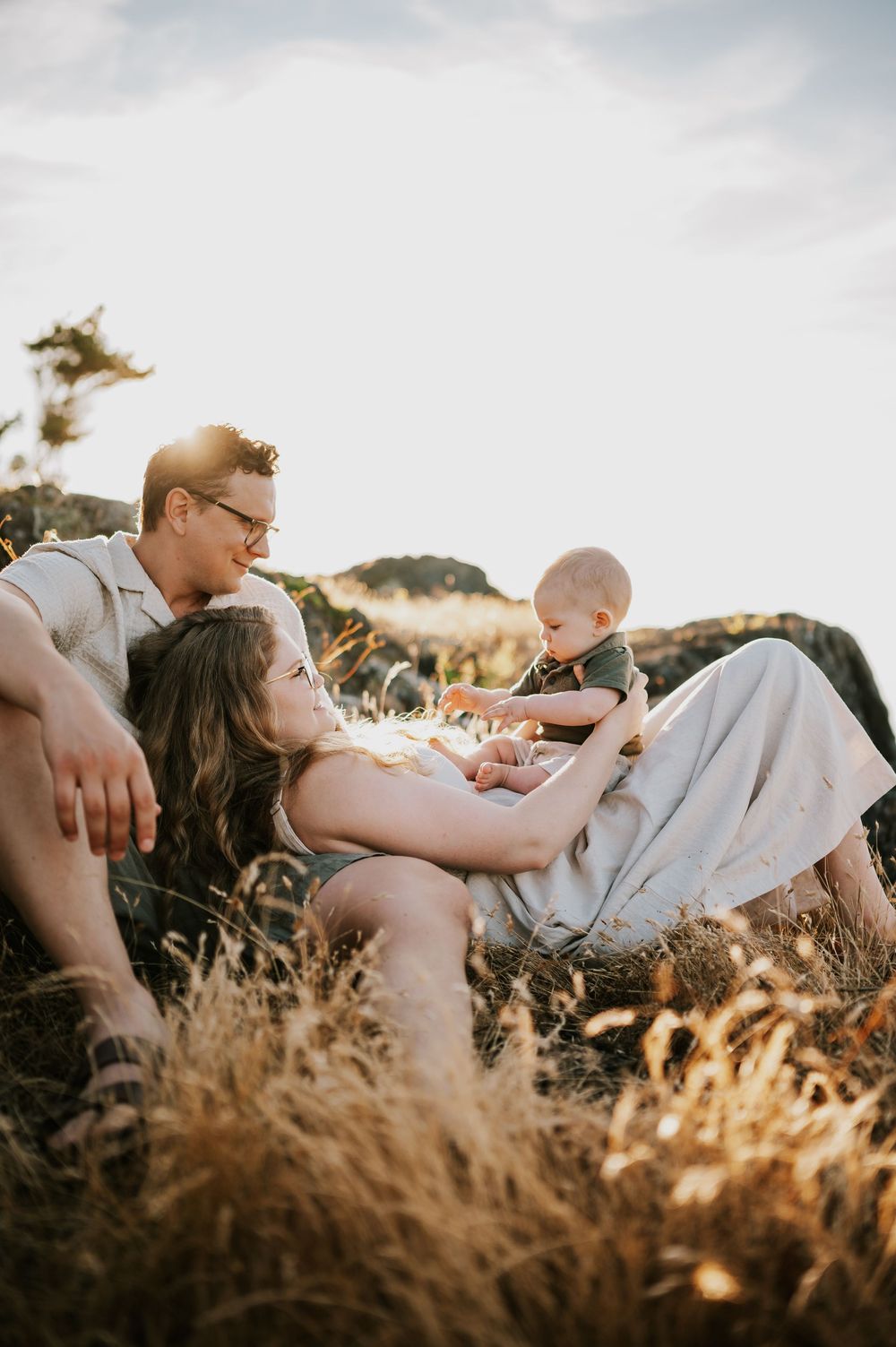 Candid photo of family sitting on rocky bluff grass Neck Point Park Nanaimo sunset family photography by Vancouver Island photographer