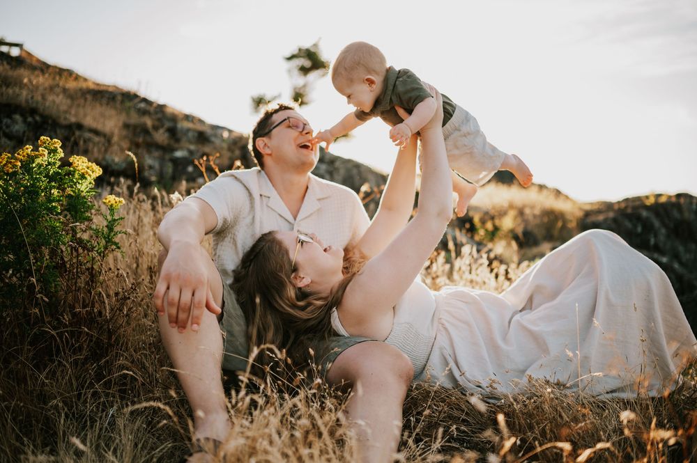 Candid photo of family sitting on rocky bluff grass Neck Point Park Nanaimo sunset family photography by Vancouver Island photographer