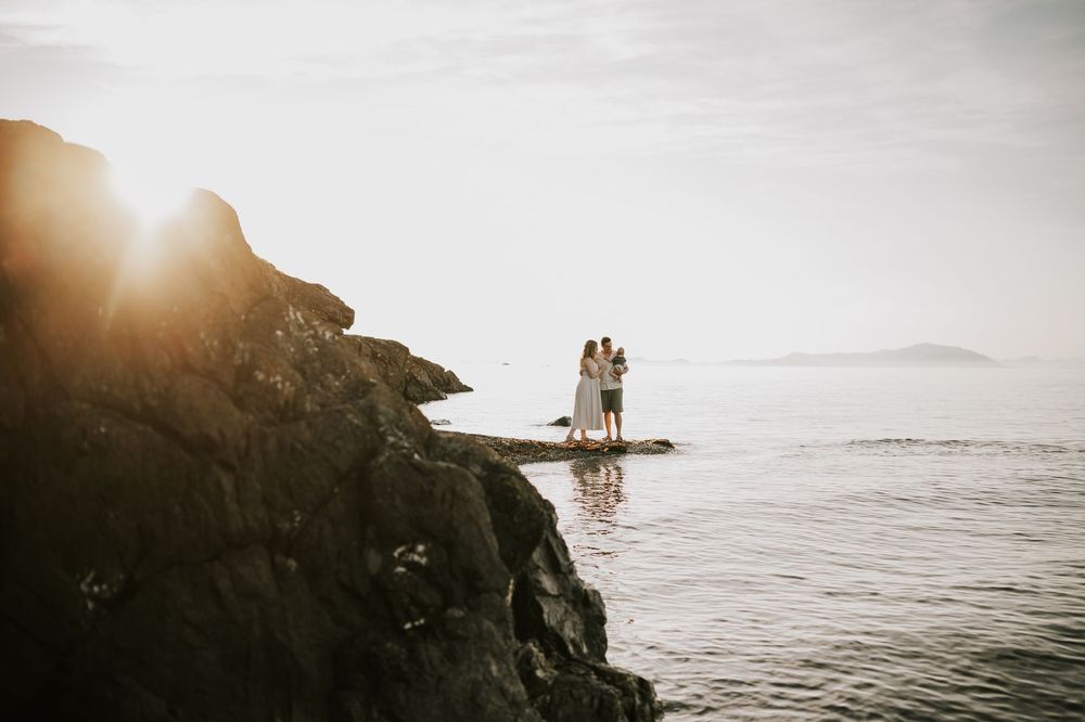 Candid photo of family hugging on rocky shore by ocean Neck Point Park Nanaimo sunset family photography by Vancouver Island photographer