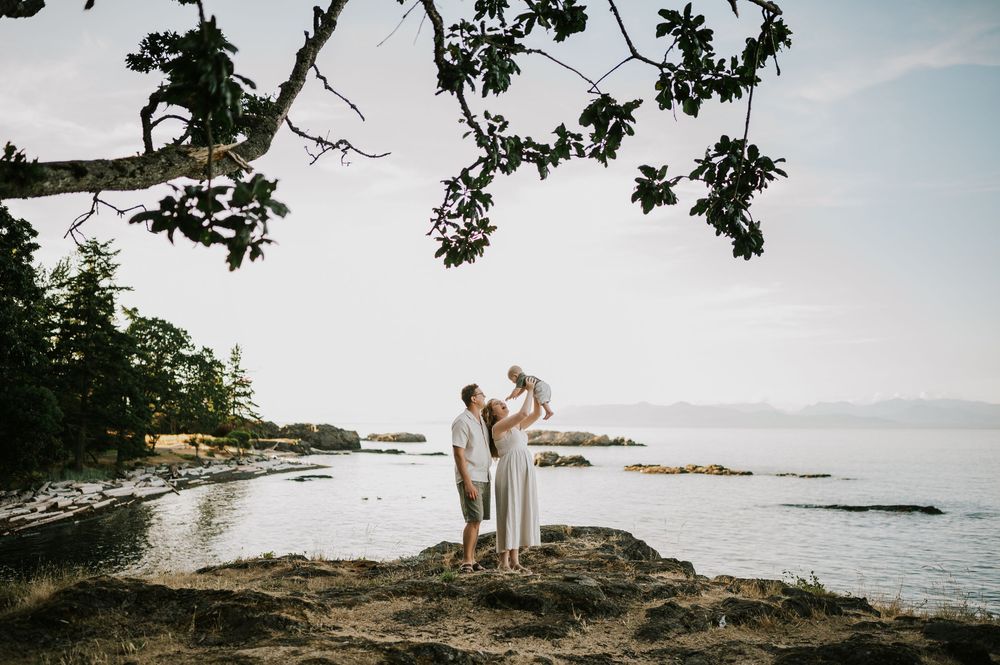 Candid photo of family holding baby at Neck Point Park Nanaimo during golden hour family photography by Vancouver Island photographer