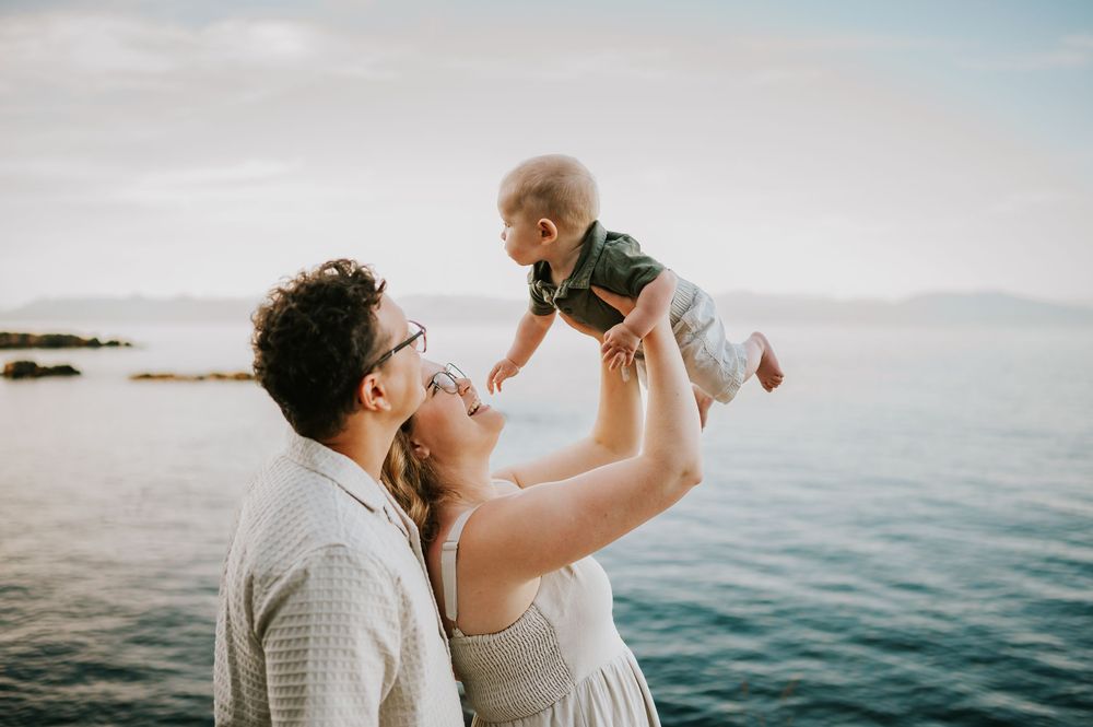 Beautiful portrait of family holding baby at Neck Point Park Nanaimo during golden hour family photography by Vancouver Island photographer
