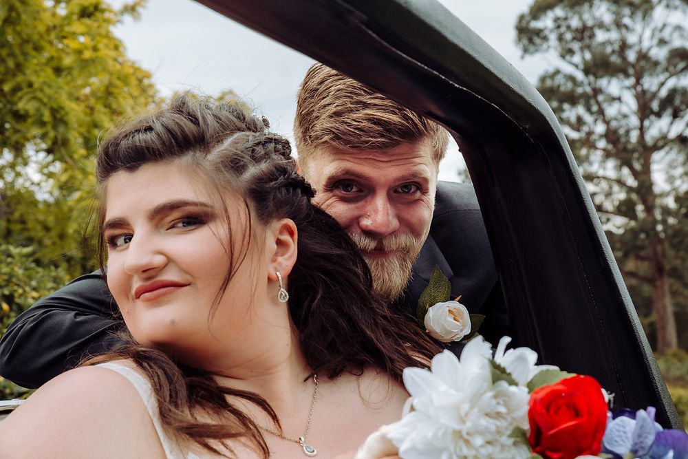 A close-up moment shared in the back seat of a car with white and red flower bouquet details.