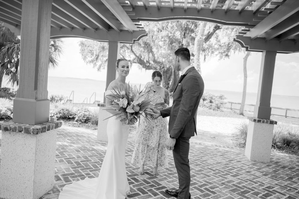 Black and white photos capture intimate moments of a wedding ceremony under covered spaces at a waterfront venue with Spanish moss.