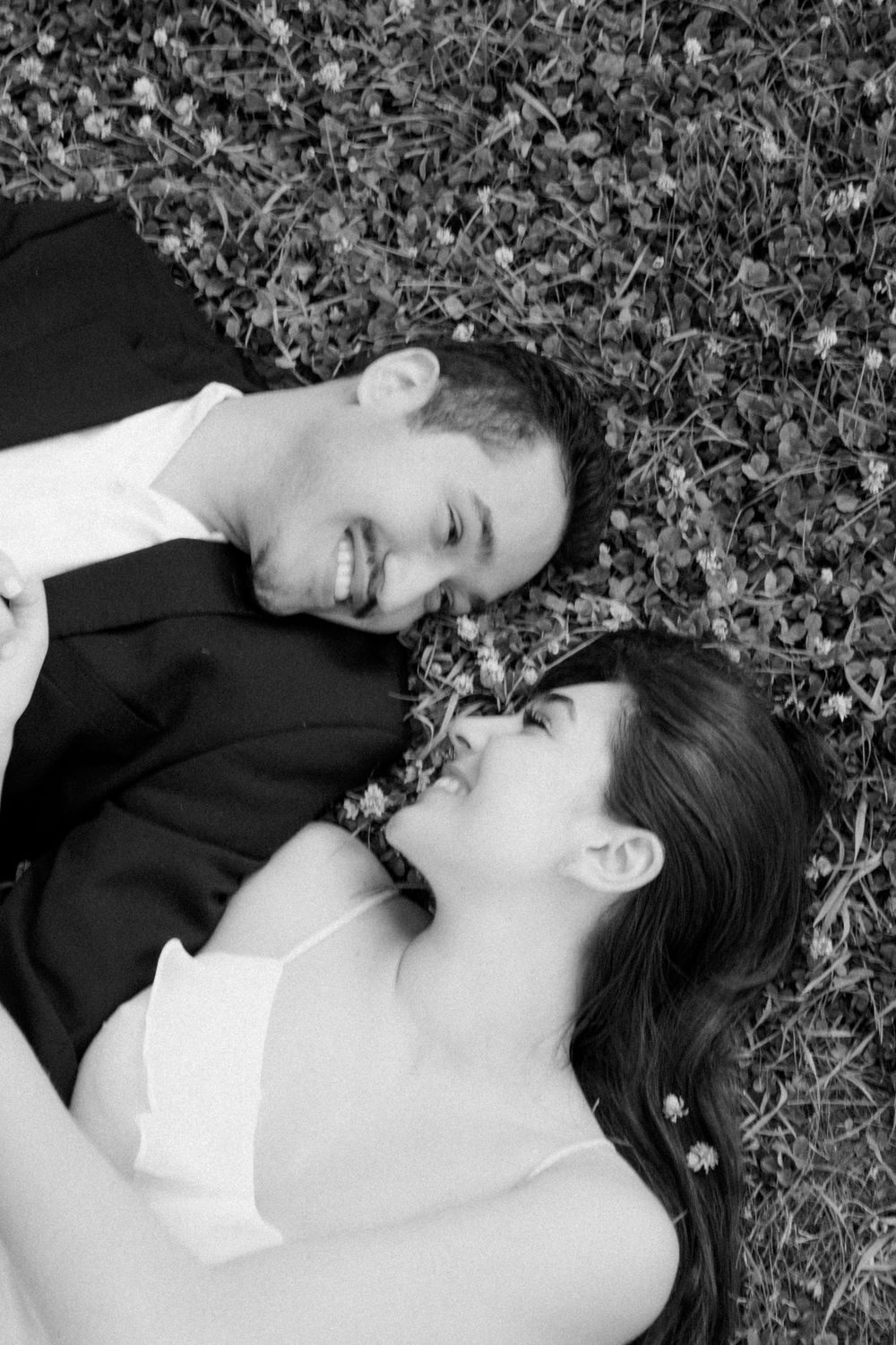 Black and white photo series of a person lying in grass and leaves while wearing dark clothing and white collar.