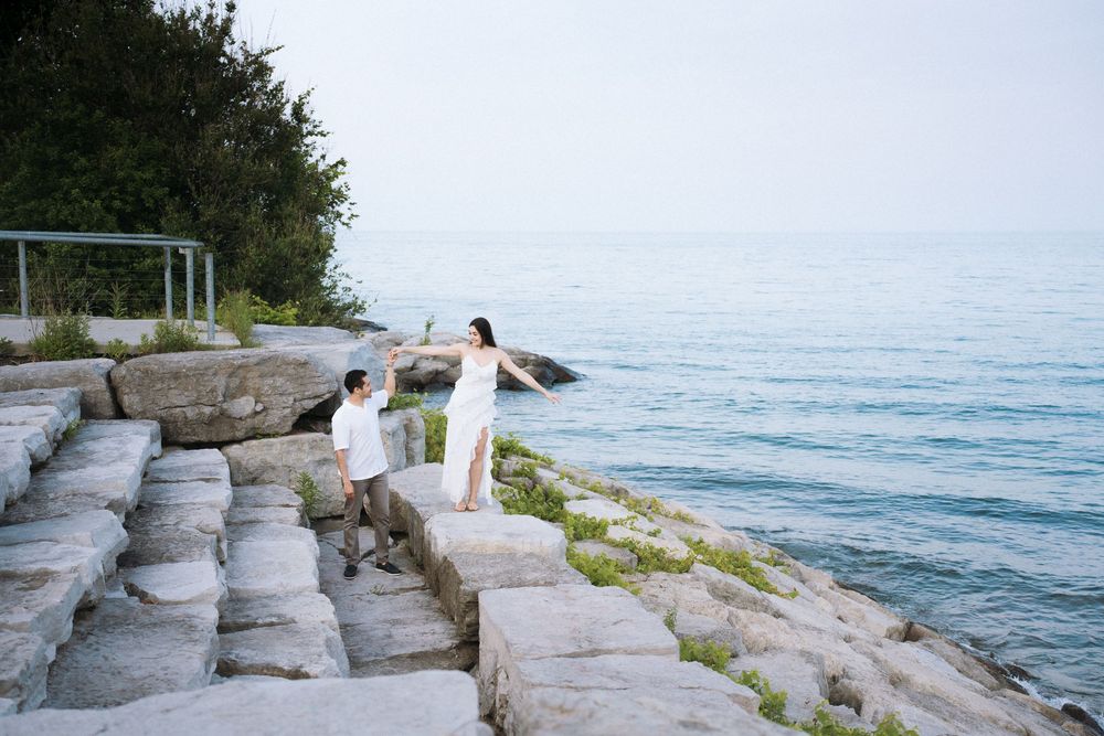 People walking down weathered stone steps near the ocean on a serene coastal landscape.
