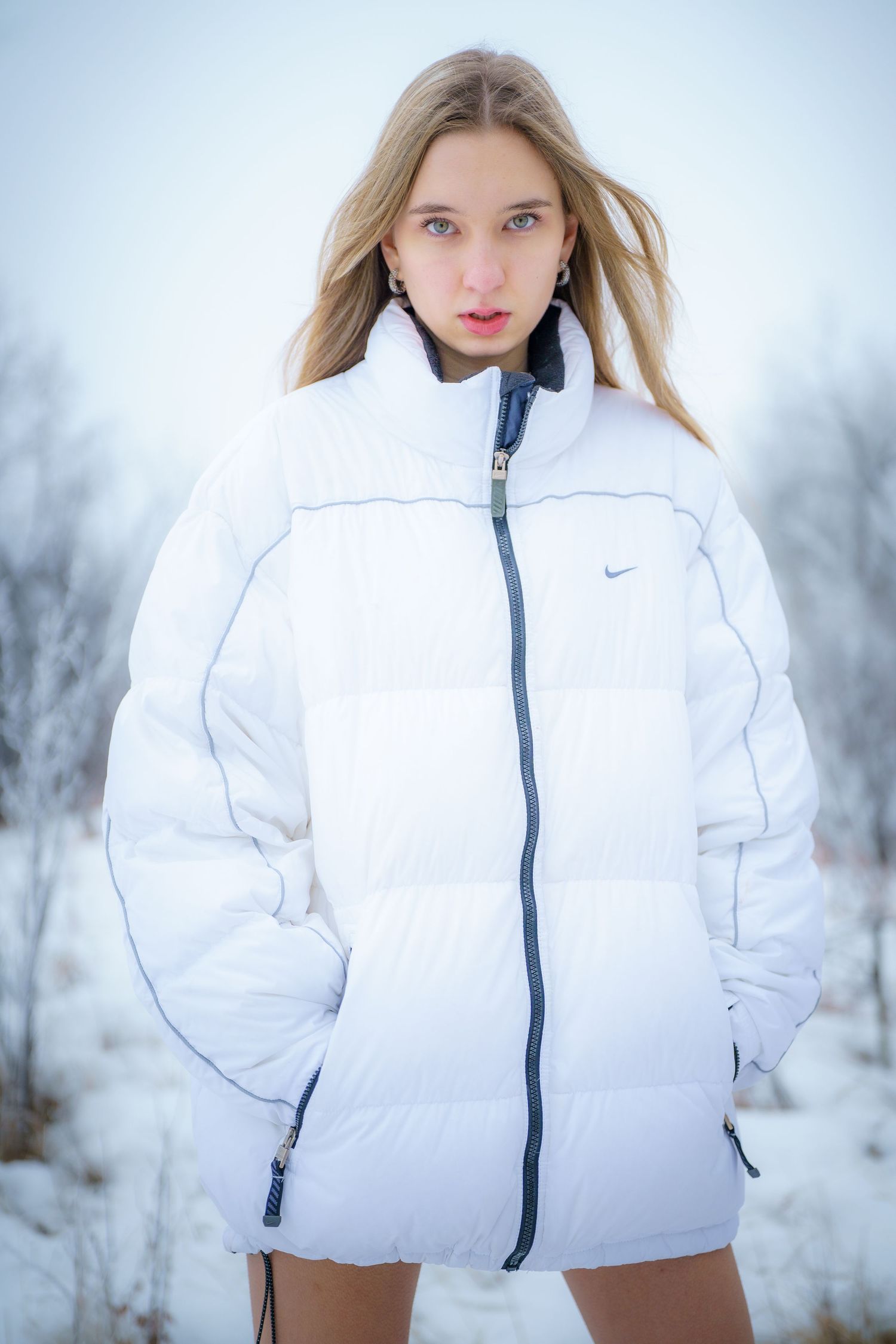 Person wearing a white Nike puffer jacket poses outdoors in a snowy winter setting.