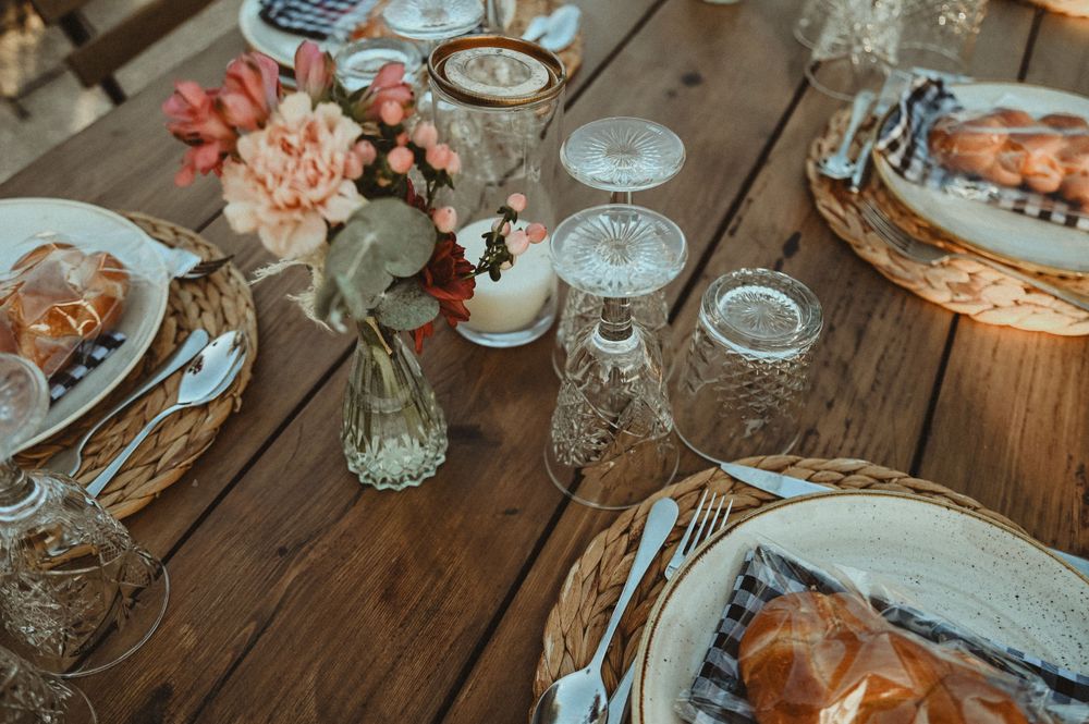A rustic wedding table setting with vintage glassware, floral centerpieces, and wooden details.