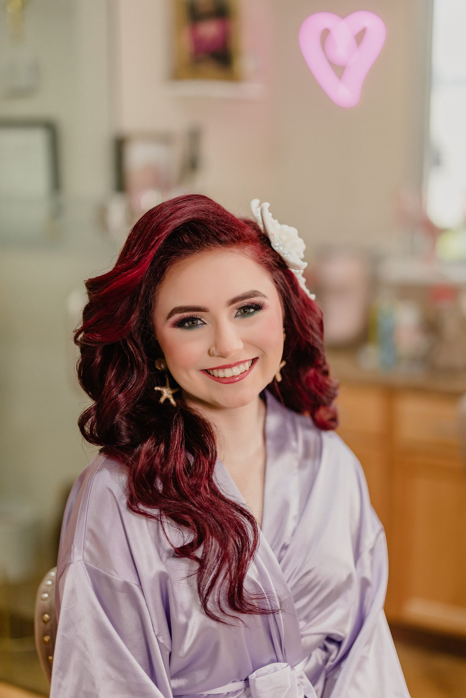 Getting ready photo showing vibrant red curls, white flower hair accessory, and lavender silk robe.