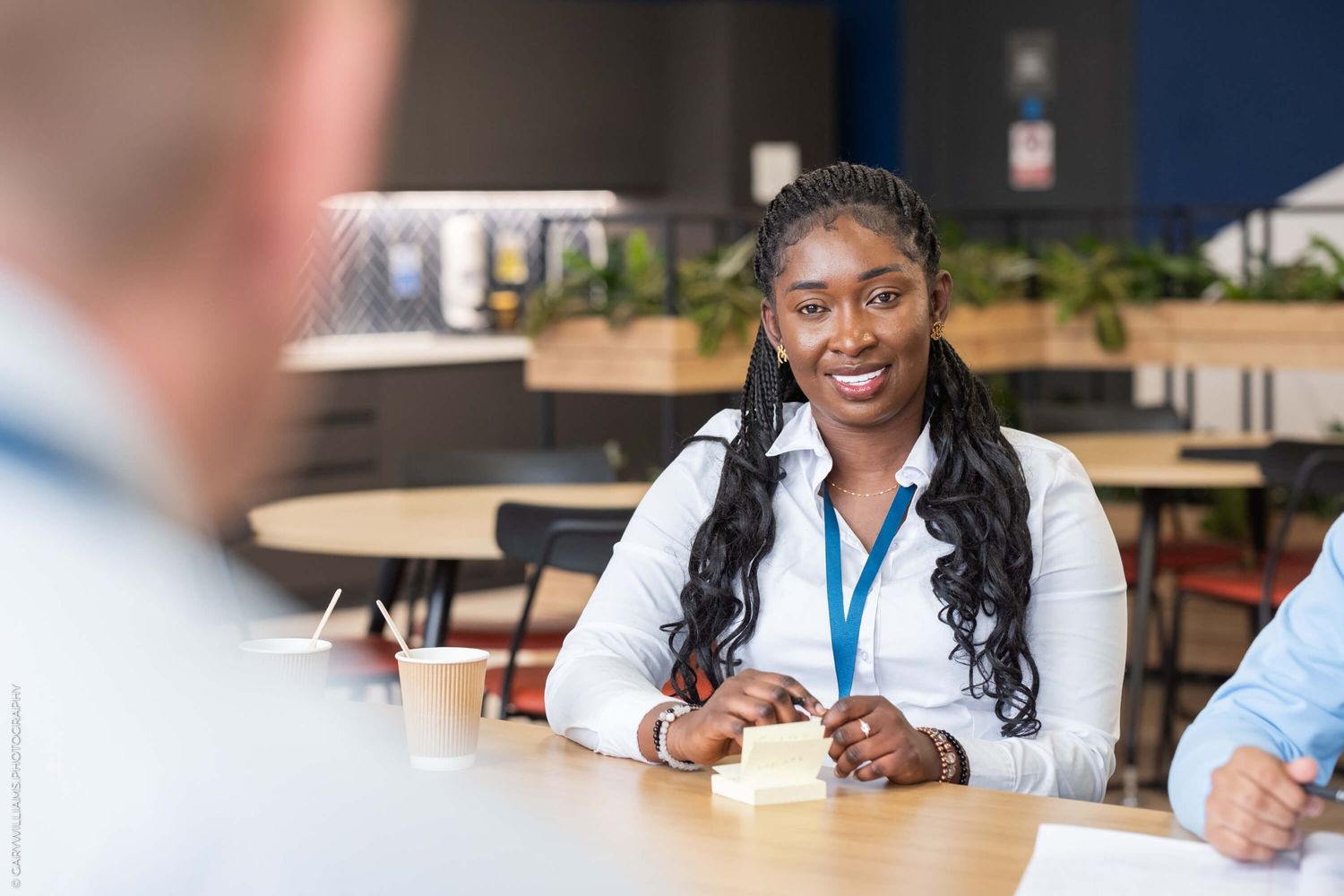 Professional in business attire smiles during a meeting in modern office space.