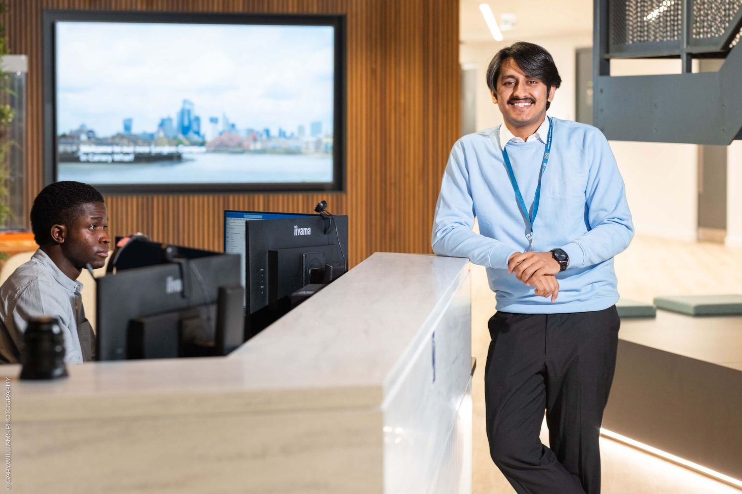 Corporate office reception area with modern design and city skyline display screen.