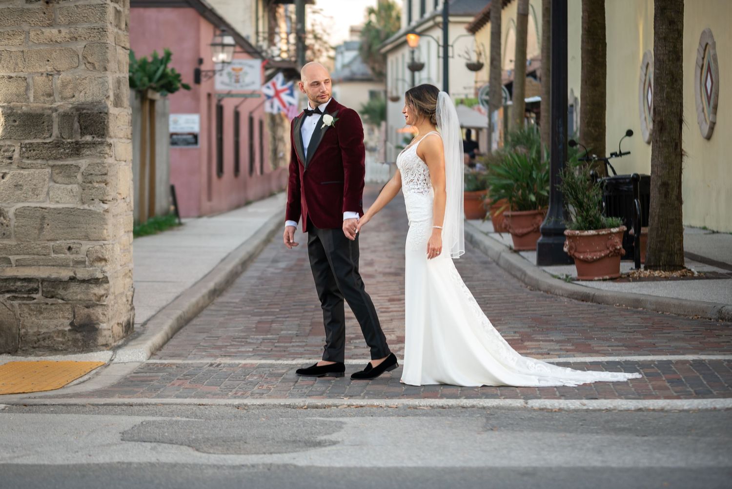 Bride and groom embrace in front of historic Spanish-style architecture in St. Augustine, captured by luxury wedding photographer in Florida
