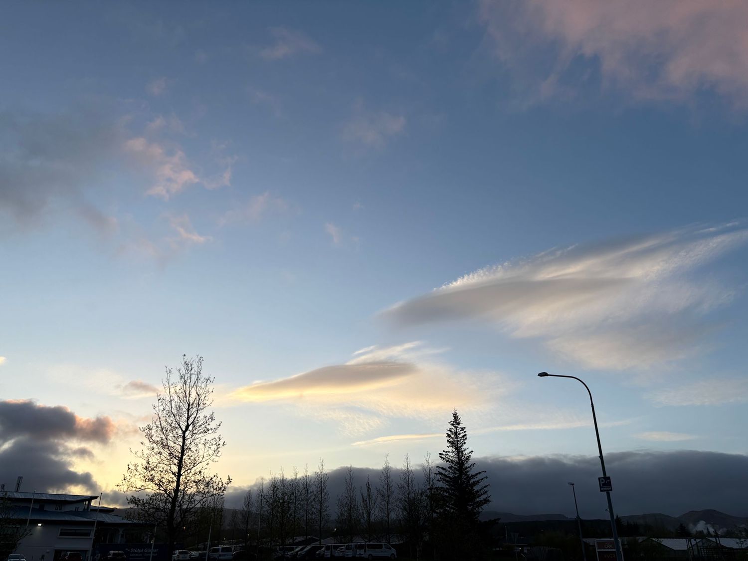 Beautiful winter sunset over mountains with silhouetted trees and dramatic clouds in the sky.