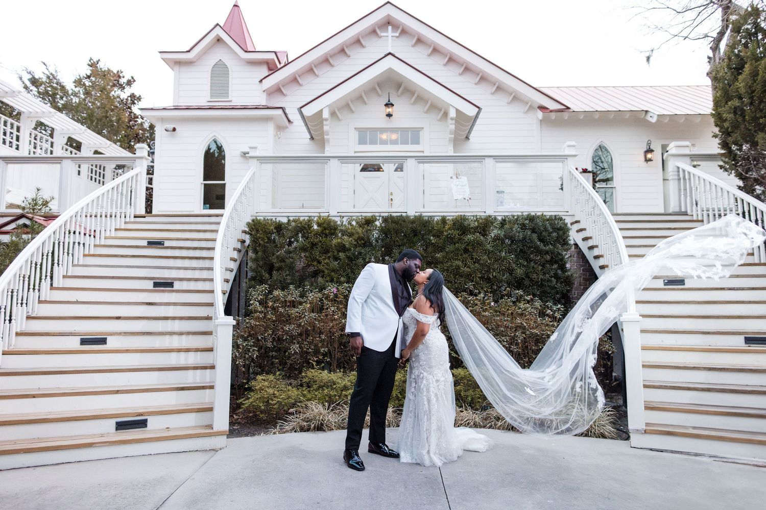 A couple shares an intimate moment at Perry House in Monterey with flowing veil and grand white staircase.