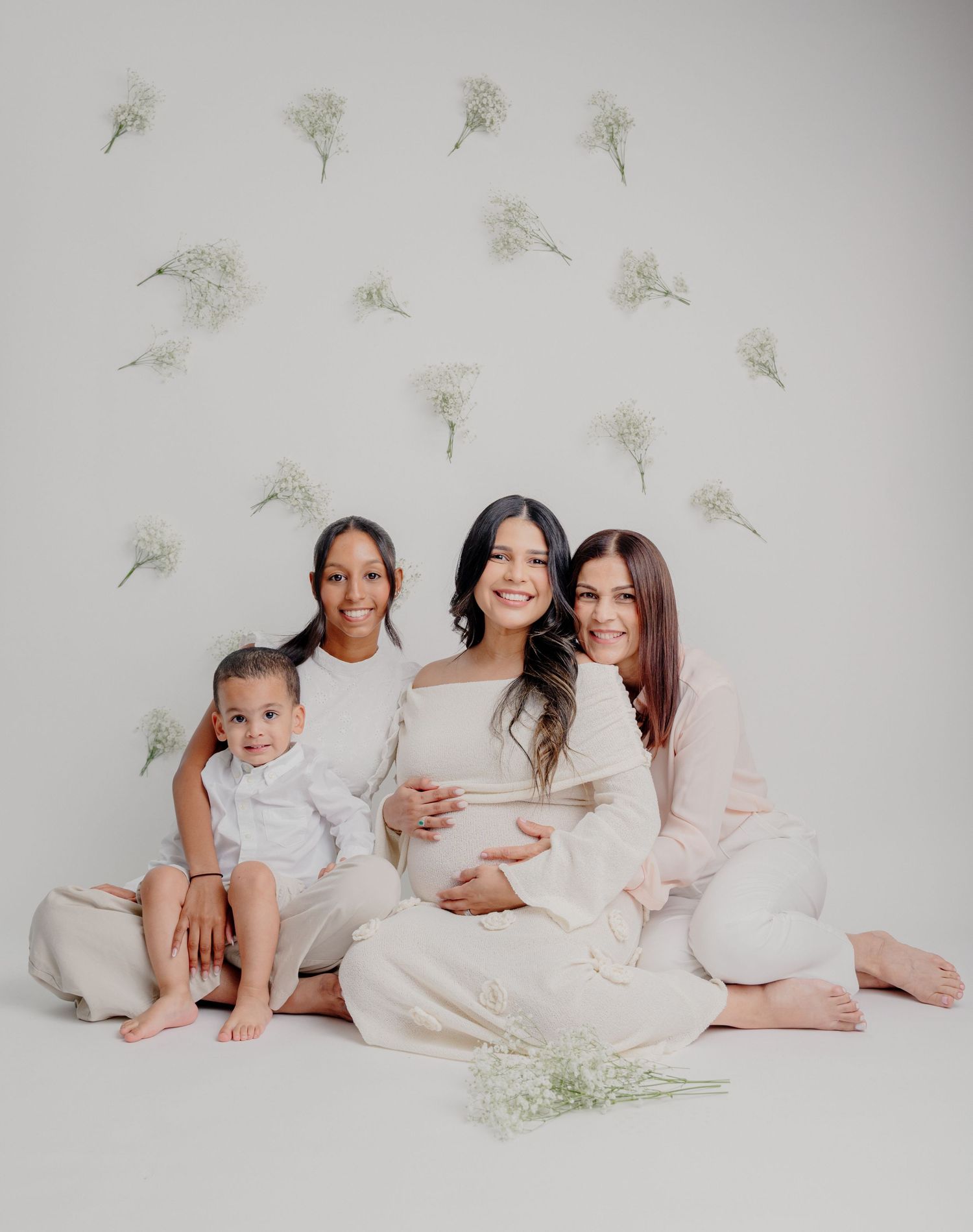 Four people in soft neutral colors sitting against a white backdrop decorated with delicate dandelion seed heads.