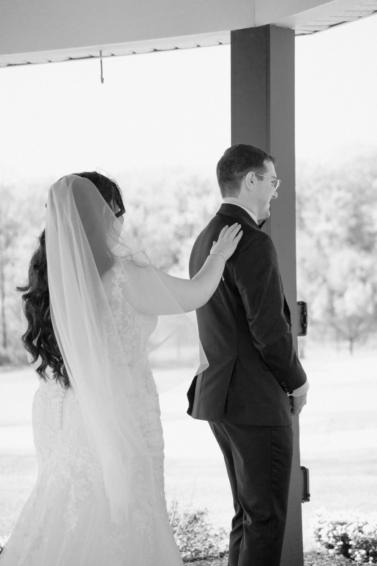 Black and white photo of wedding couple during first look moment outdoors.