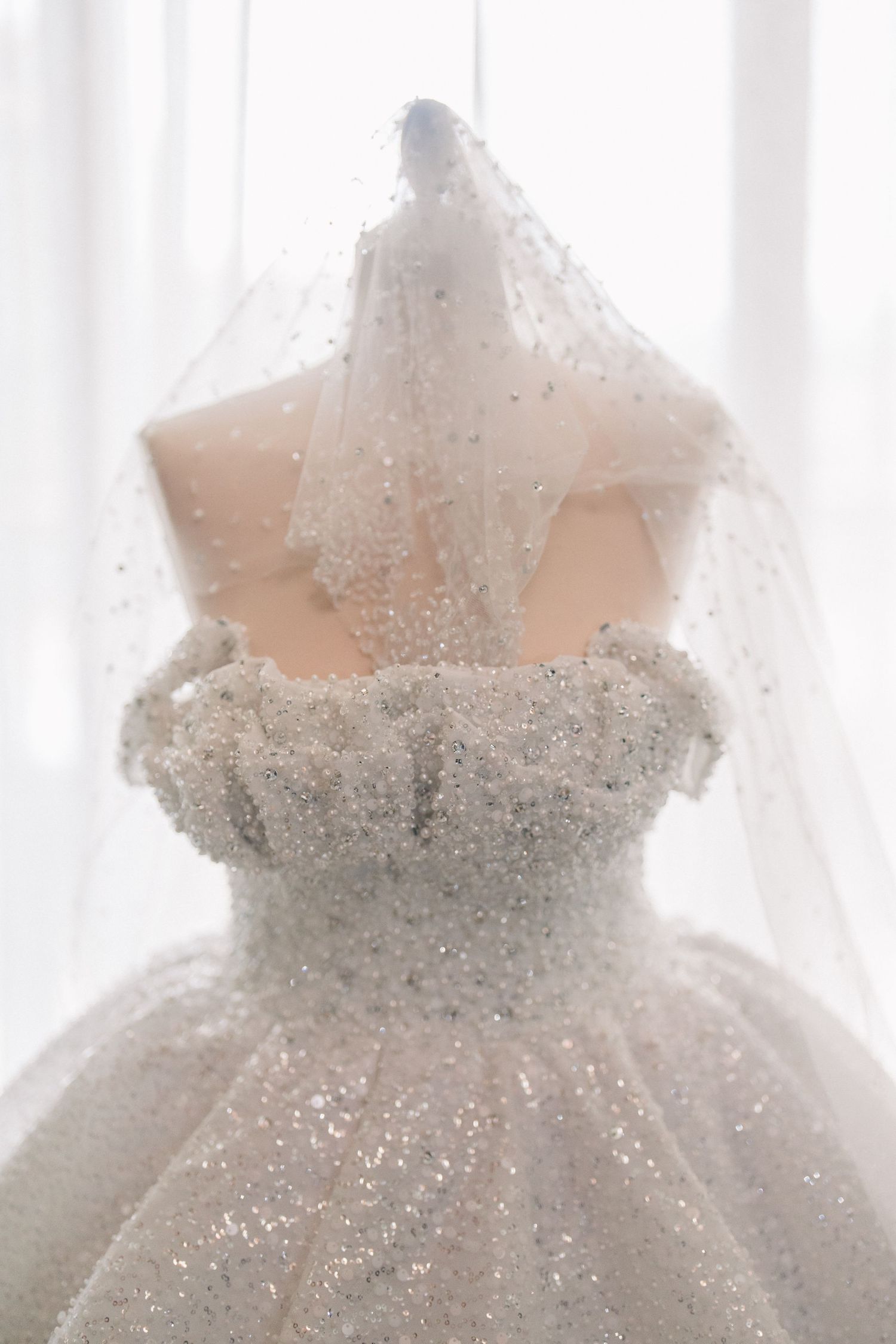 A white sparkly wedding dress with a sweetheart neckline and veil covered in glitter and beading.