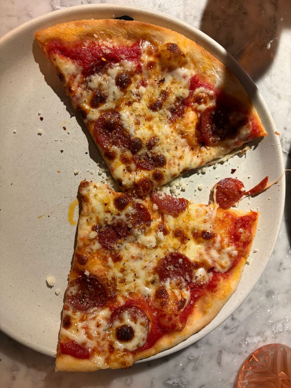 Half eaten pepperoni and cheese pizza on a white plate with red tomato sauce and melted mozzarella.