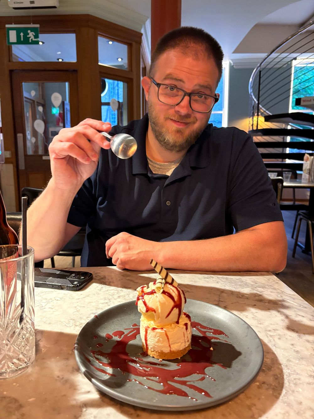 A dessert plate features a decadent ice cream dessert with chocolate sauce artfully drizzled on a gray plate in a restaurant setting.