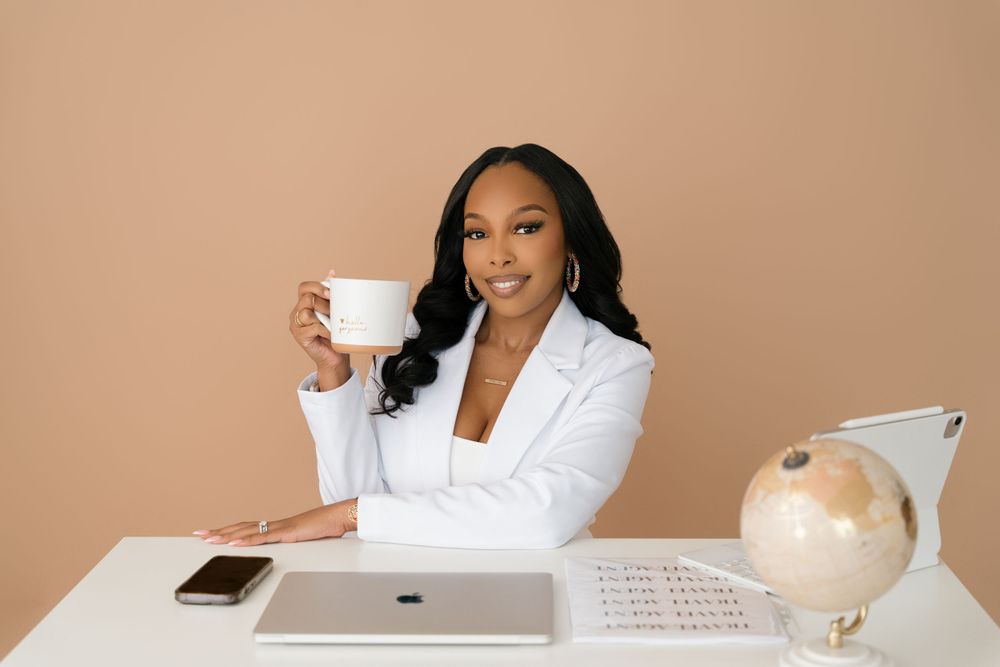 Professional at modern white desk with laptop, coffee cup, and decorative globe against beige background.