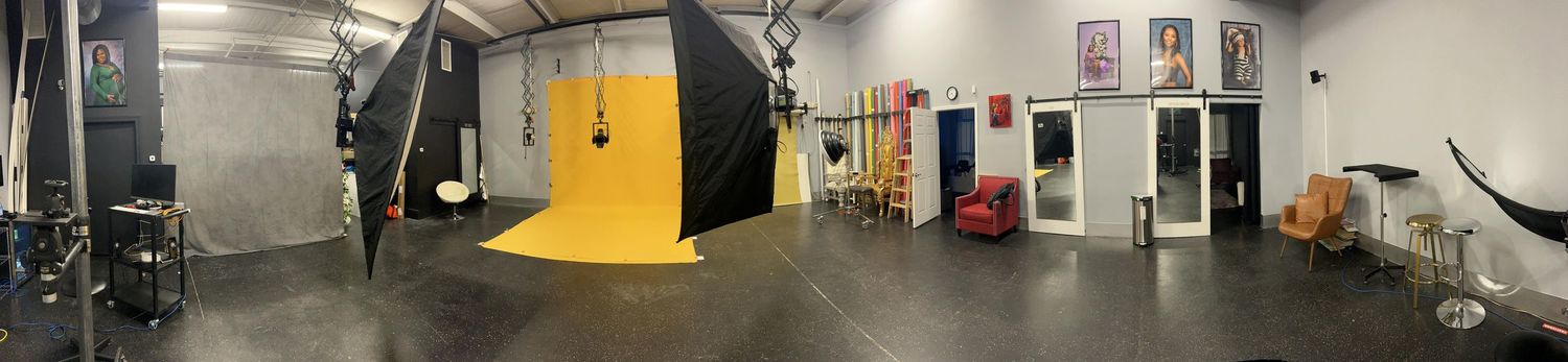 Panoramic view of a professional photography studio with lighting equipment and colored backdrops.