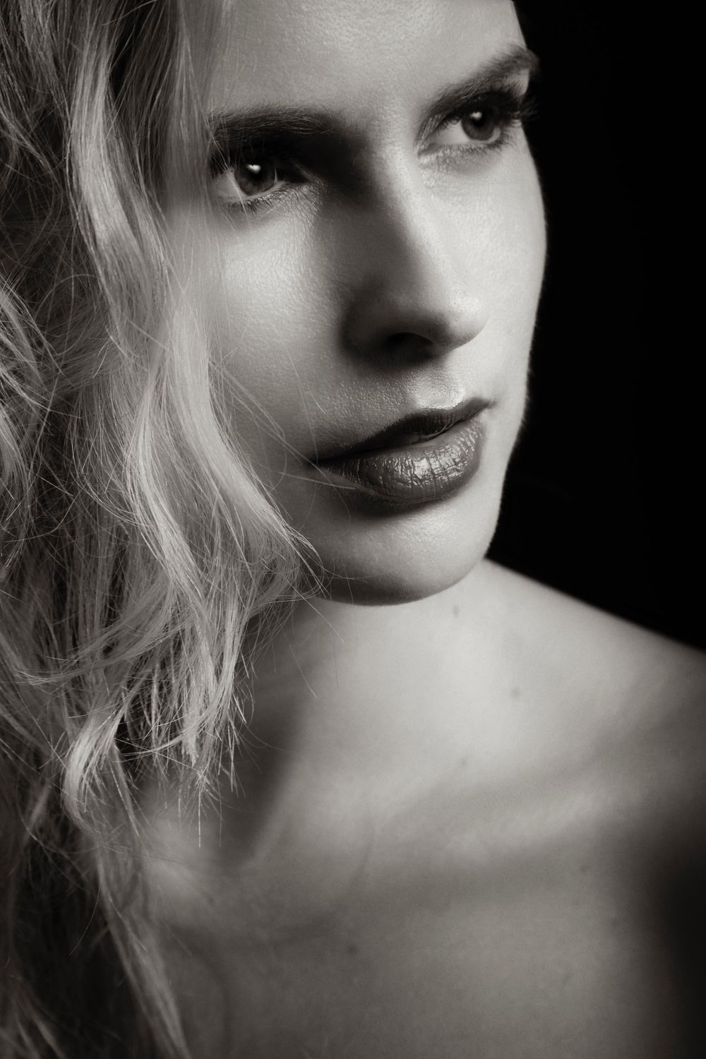 Black and white dramatic portrait of Natalia showing blonde hair, defined features and moody lighting with dark shadows photographed by Evan