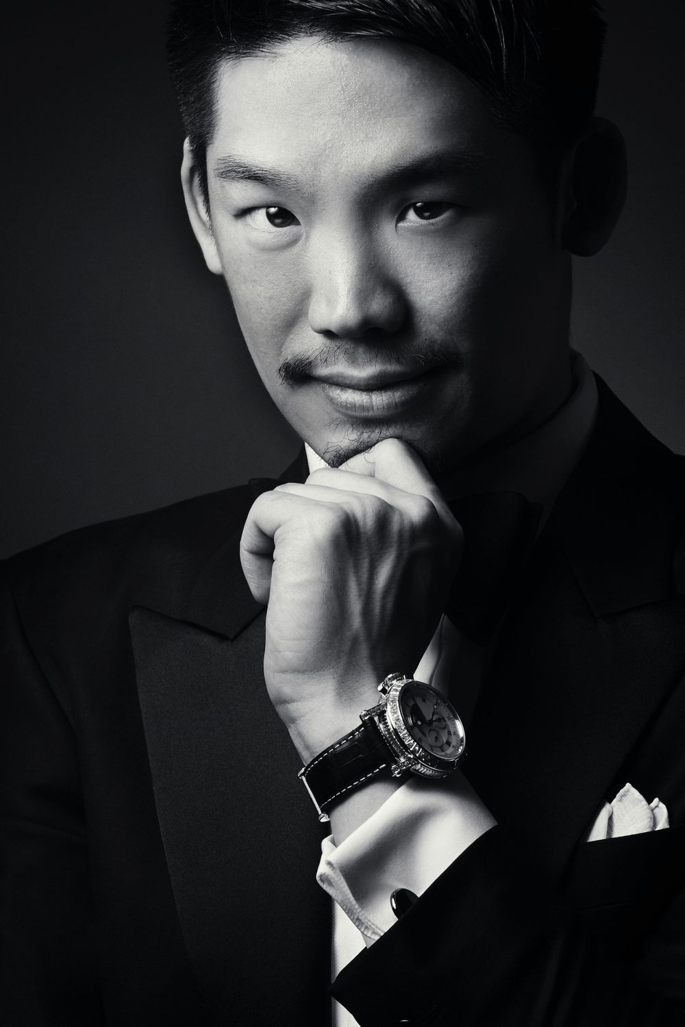Professional black and white portrait of person in formal suit with hand on chin wearing luxury watch photographed by Evan Will of Sharko