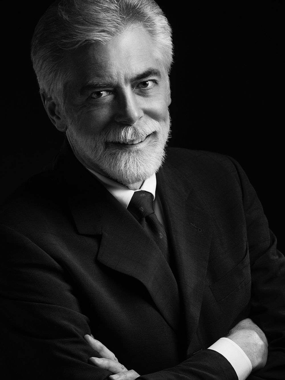A black and white professional portrait of Ed Valentine with white hair and beard wearing a dark suit photographed by Evan Will