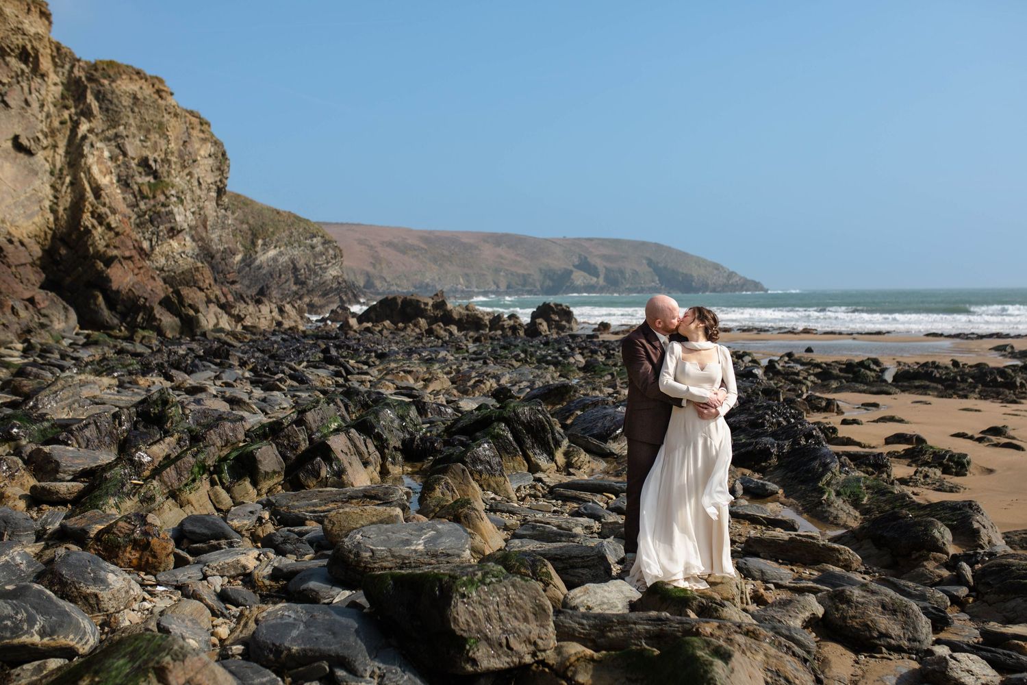 Scenic coastal engagement photo shoot featuring rugged rock formations and expansive ocean views at sunset beach.