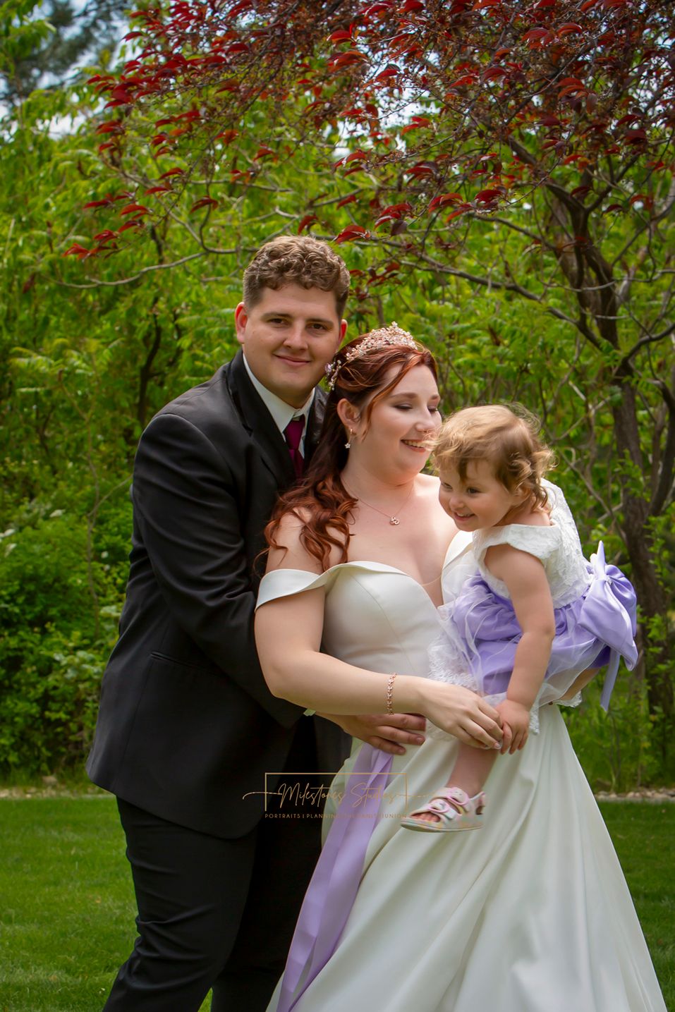 bride and groom holding 2-year-old daughter
