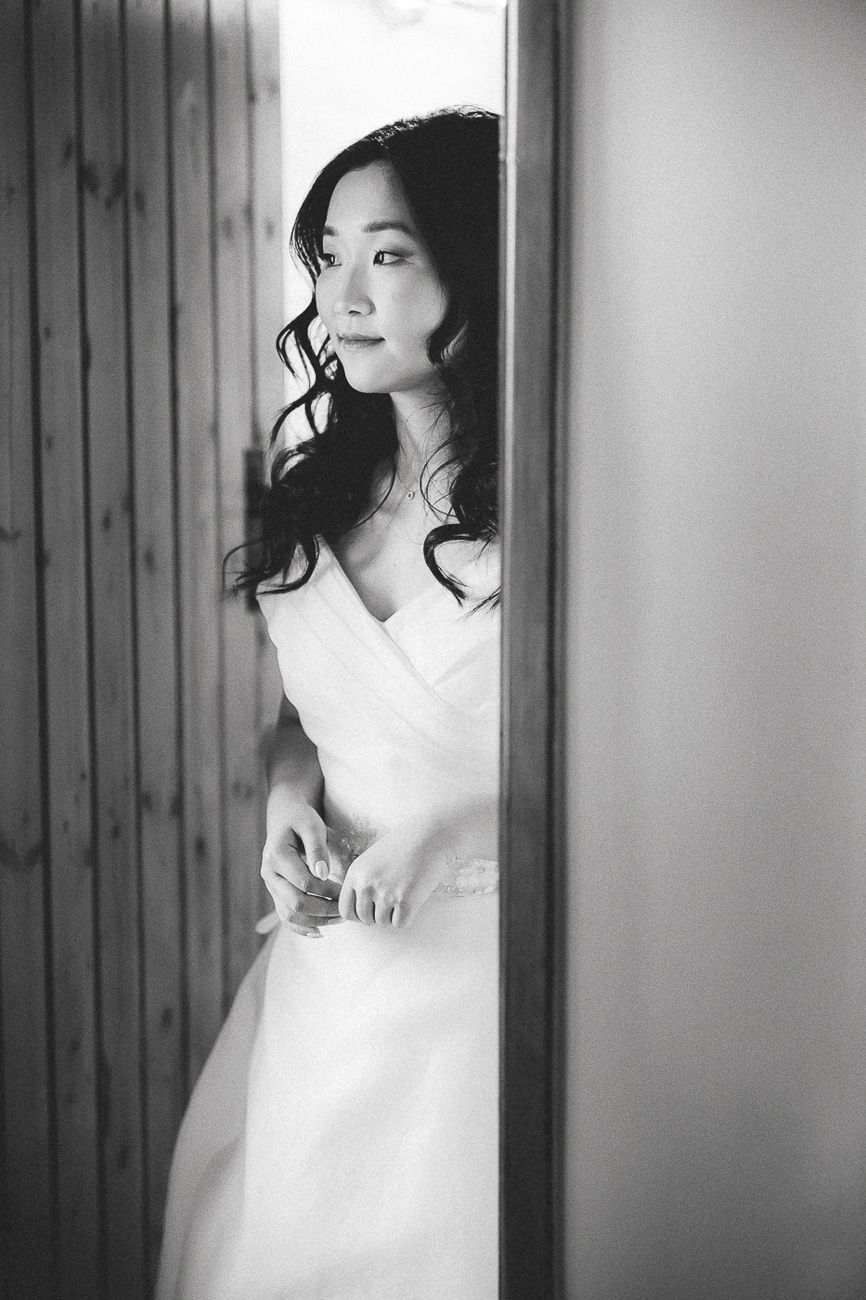 Black and white portrait series showing a figure in a white dress posing elegantly against a wooden wall.