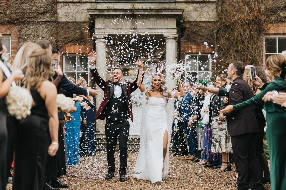 Wedding party and guests celebrate with confetti during an outdoor celebration ceremony.