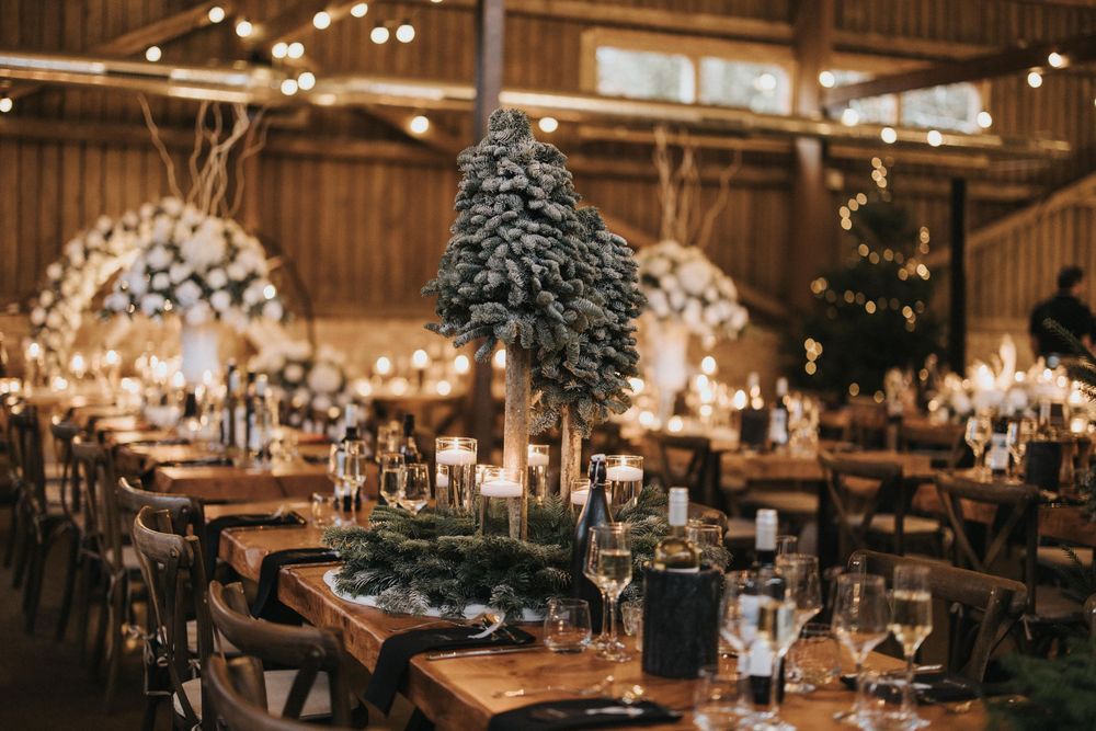 A rustic wedding reception venue with warm lighting, wooden beams, and elegant table settings with floral centerpieces.