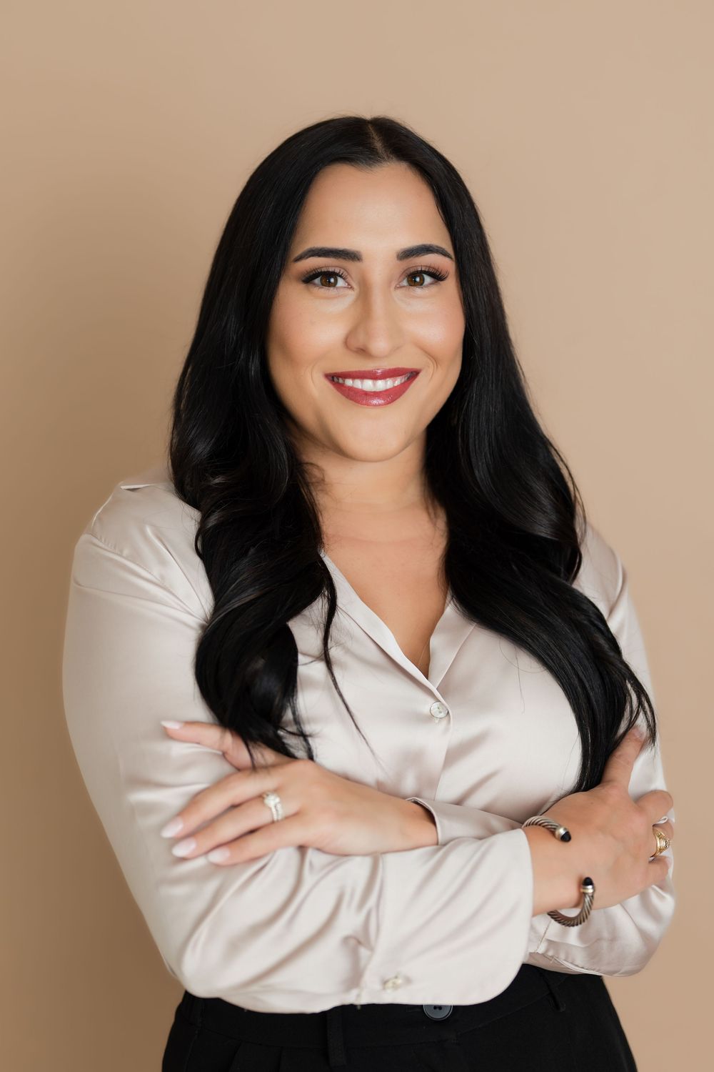 Professional headshot of someone with long dark hair wearing a cream blouse against a neutral background.