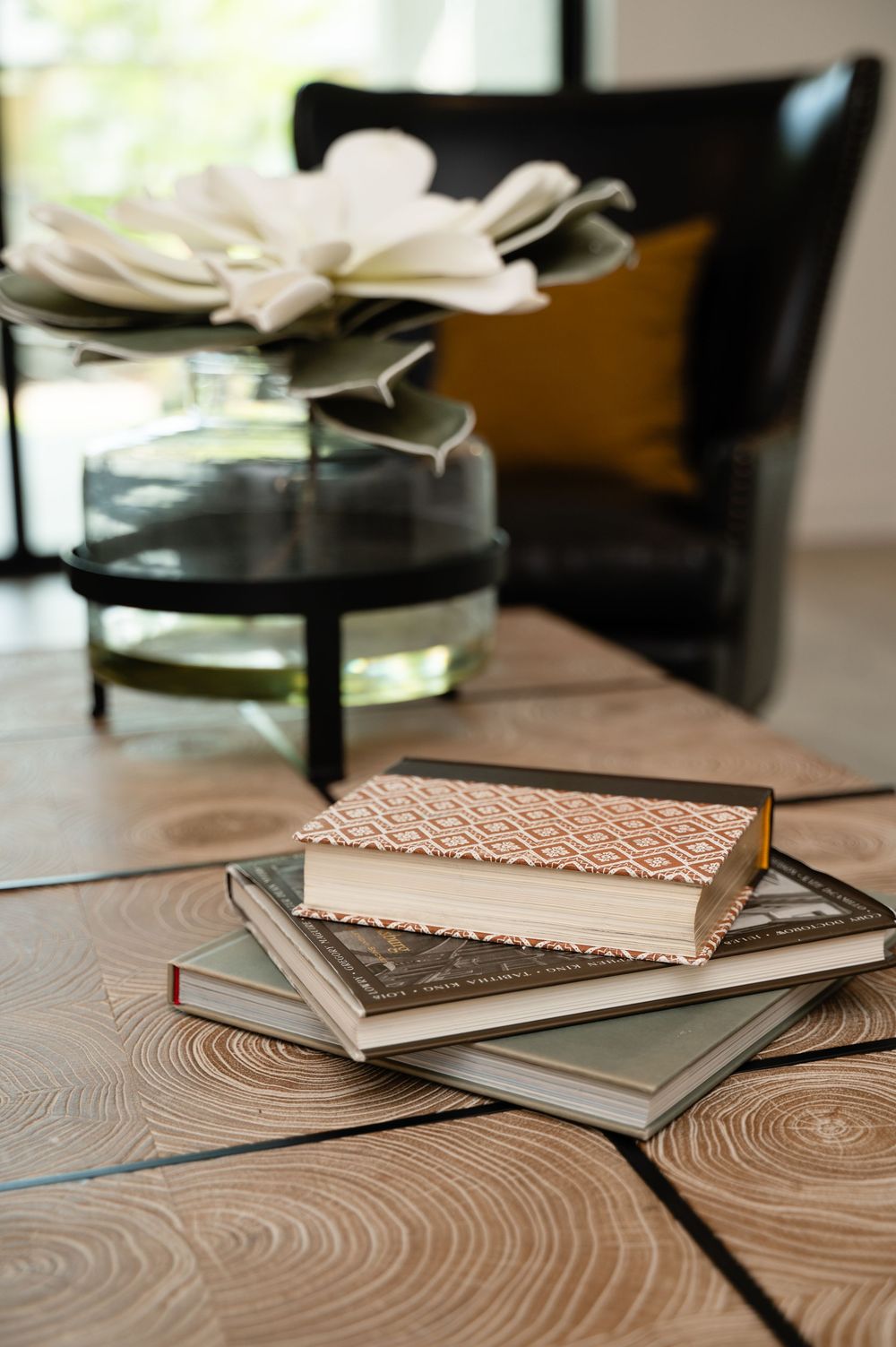 A series of cream colored hardcover books with textured covers arranged in a diagonal line on a wooden surface.