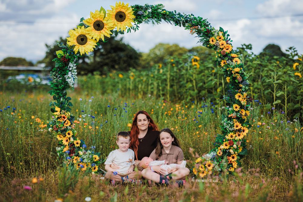 Sunflower arch decorated with greenery creates magical setting in wildflower meadow.