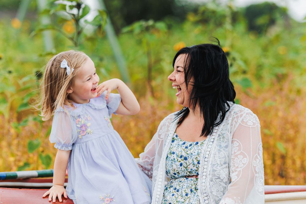 A joyful outdoor portrait showing laughter and connection amidst greenery and natural light.