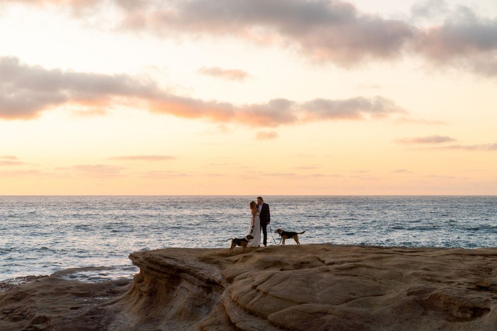 Silhouette of figures against dramatic sunset sky at ocean overlook.